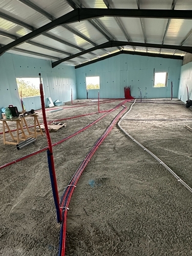Instalación de cableado en el suelo de una nave industrial.