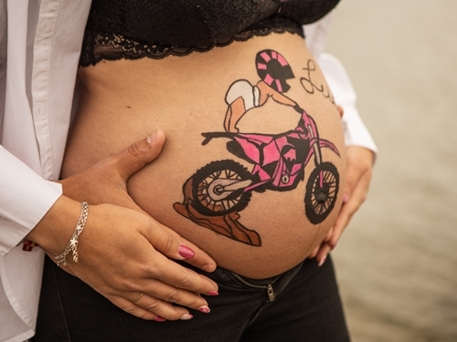 Mujer embarazada mostrando una ecografía pintada en su barriga.