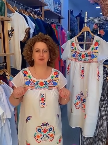 Dueña o empleada de Modas Cerrato posando con una blusa bordada.