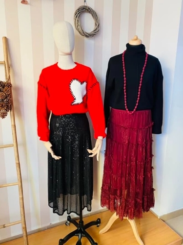Maniquí con un conjunto de falda roja, jersey y accesorios oscuros.