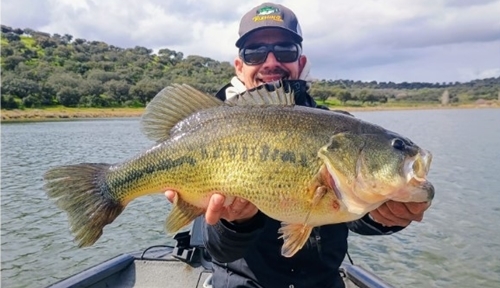 Un pescador sujetando un gran black bass