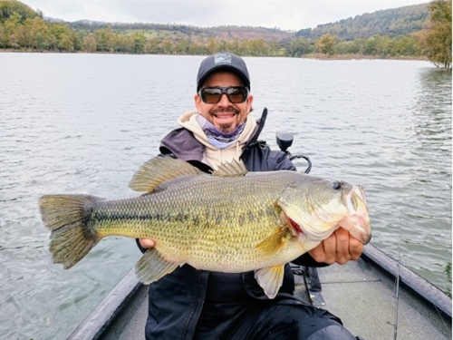 Pescador en un barco en un embalse con black bass